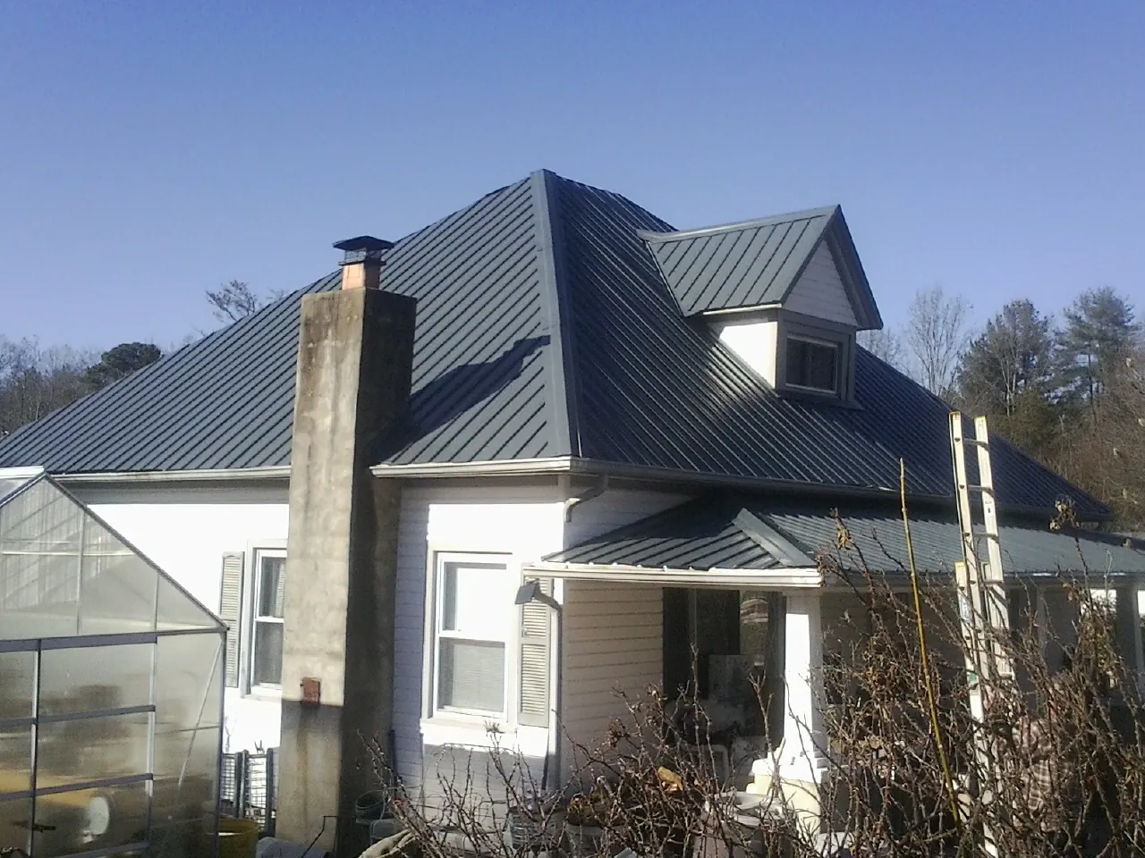 Dark blue standing seam metal roof on a white farmhouse with dormer — Slate & Tile Roof Repair by Roofing Brothers in Gig Harbor