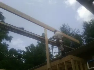 Carpenter setting a ridge beam over a new addition frame — Ice Dam Removal by Roofing Brothers in Gig Harbor