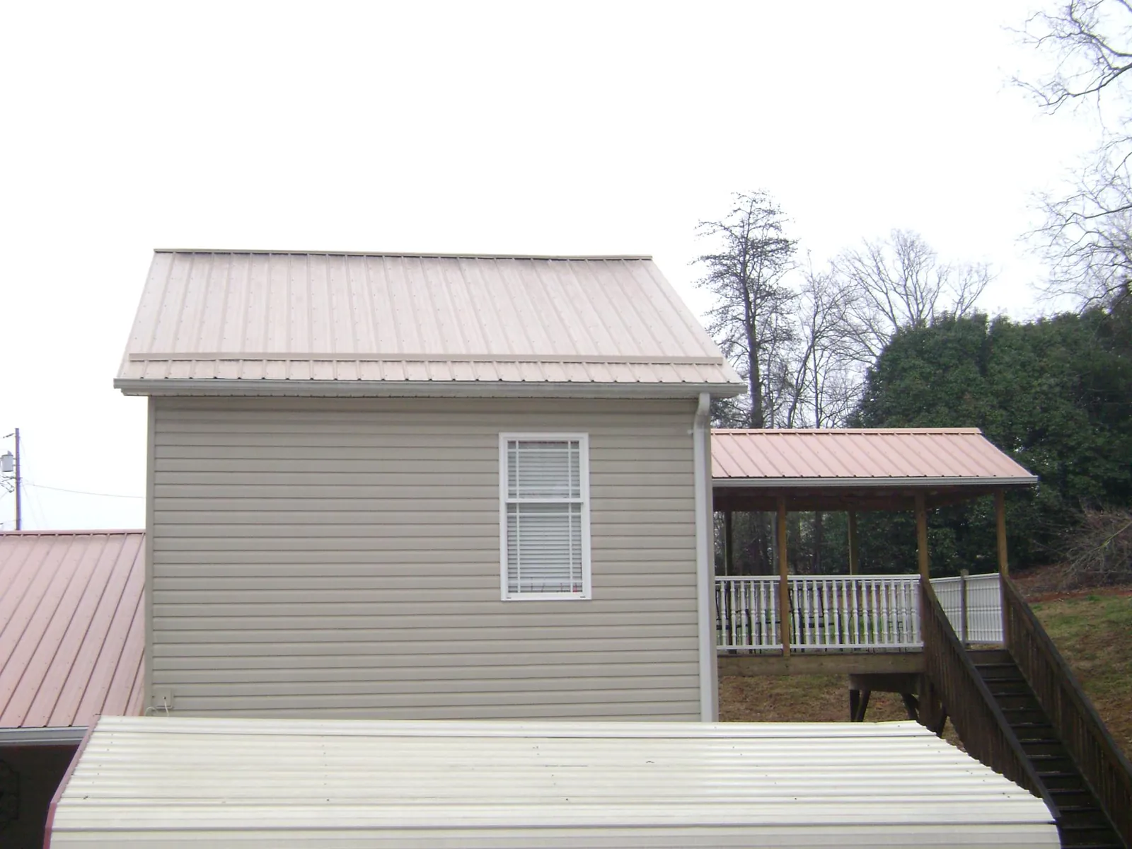 Tan metal roofs on a two story addition and attached porch, from a Roof Replacement job in Gig Harbor