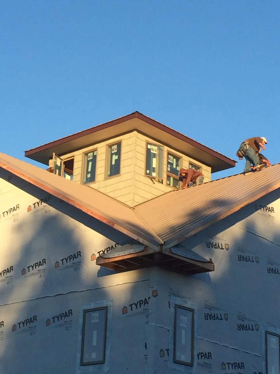 Roofers working around a rooftop cupola on a new metal roof at sunset — Roof Waterproofing in Gig Harbor by Roofing Brothers